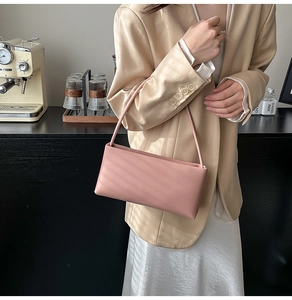 Chic pink rectangular underarm bag held by model wearing a beige blazer and silk skirt