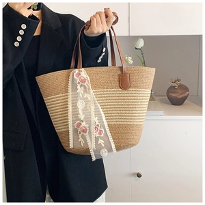 Detail view of woven straw tote bag with floral lace scarf and brown leather handle