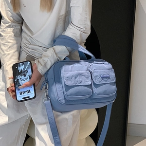 Model wearing a blue nylon multi-pocket crossbody bag with adjustable shoulder straps