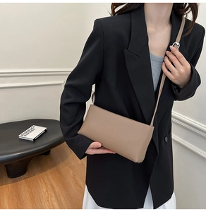 Minimalist khaki rectangular shoulder bag shown on model with adjustable strap and silver buckle