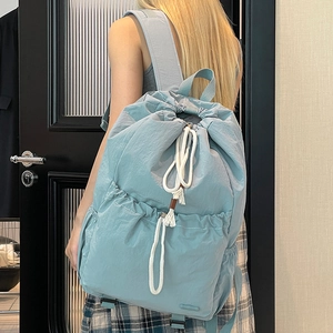 Detailed back view of a light blue nylon drawstring backpack worn on a model