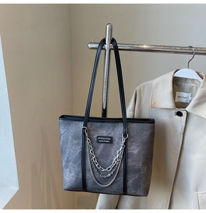 Détail du sac fourre-tout gris texturé avec chaînes argentées et anses en cuir noir
