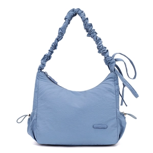 Detail view of fog blue nylon bag featuring soft ruched strap and drawstring bow