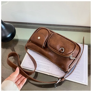 Detail of a dark brown vintage shoulder bag with dual front pockets on stylish magazines