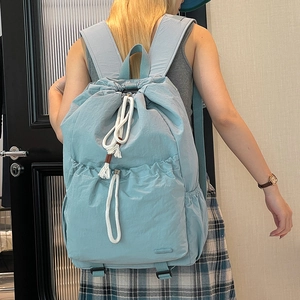 Close-up of light blue nylon drawstring backpack with white rope detail and side pockets