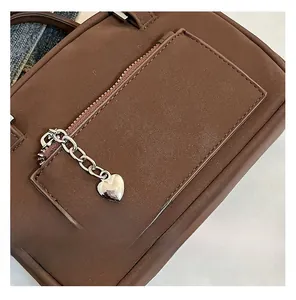 Détail du sac polochon marron mat avec breloque cœur argentée et fermeture éclair