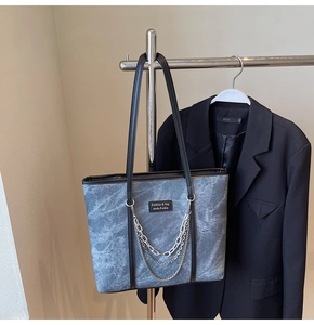 Détail d'un sac cabas gris avec texture marbrée et chaînes argentées décoratives
