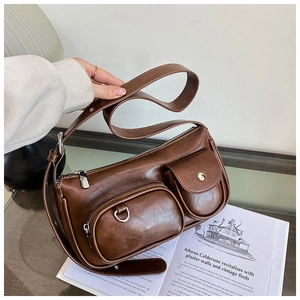 Macro shot of brown PU leather shoulder bag featuring dual front pockets and silver hardware