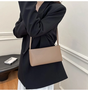 Mocha leather underarm bag shown on model in a minimalist modern interior setting