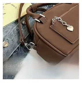 Détails de couture sur un sac bandoulière marron avec une tirette de zip en forme de cœur