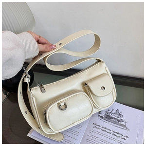 Detail of cream multi-pocket shoulder bag with silver eyelets on wide strap