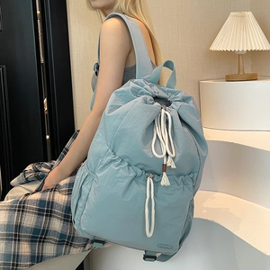 Detail of light blue nylon drawstring backpack with stylish white rope decoration