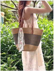 Detail of straw tote with black stripes, leather handles and floral lace scarf
