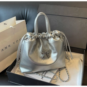 Macro detail of silver pleated handbag featuring metallic bow and chain strap design
