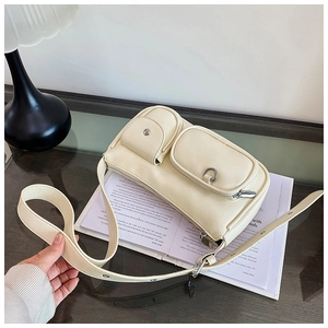 Detail view of cream crossbody bag featuring dual external pockets and wide shoulder strap