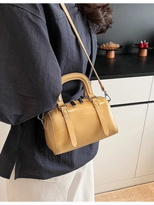 Yellow glossy patent leather Boston bag shown on model with top handle and strap