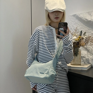 Close-up of light blue nylon hobo bag with drawstring pleats and adjustable shoulder strap