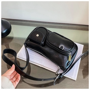 Detail of black chic handbag with silver hardware and pockets on a glass table