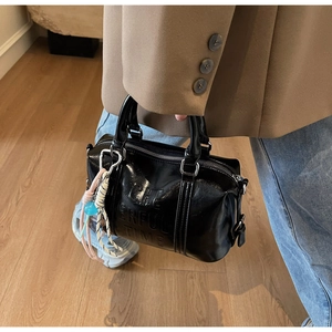 Detail shot of a black glossy Boston bag with embossed text and rope charm