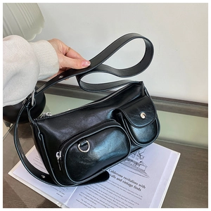 Detail of black stylish shoulder bag with metallic buckle and functional front pockets
