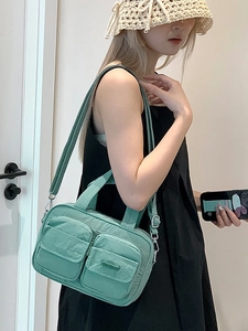 Mint green nylon crossbody bag with dual front pockets and adjustable shoulder strap