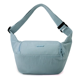 Détail du sac bandoulière en nylon bleu-gris montrant les zips et le patch du logo