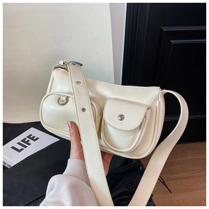 Detail view of cream crossbody bag with silver hardware buckles and utility pockets