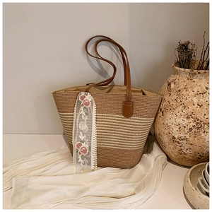 Close-up of woven tote bag with floral lace ribbon and brown faux leather straps