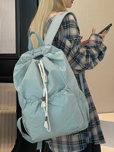 Minimalist light blue nylon drawstring backpack shown on model for casual travel use