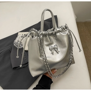 Detailed view of metallic silver drawstring tote bag with bow accent and chain strap