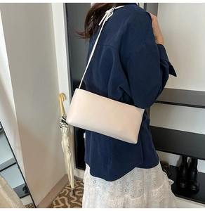 Model wearing a minimalist cream beige underarm shoulder bag in high quality synthetic leather