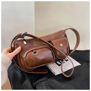 Close-up of a dark brown leather crossbody bag with dual functional front pockets and silver hardware