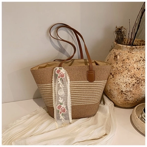 Detail of handwoven straw tote bag with delicate rose embroidery scarf on white silk