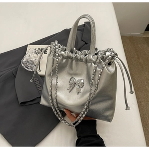 Detail of silver drawstring tote bag with metallic bow and elegant chain strap