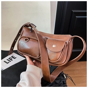 Detail of dark brown vintage underarm bag with glossy leather texture and front pockets