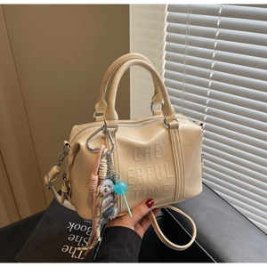 Close-up of beige Boston handbag featuring Cheerful Time embossed logo and cute charms