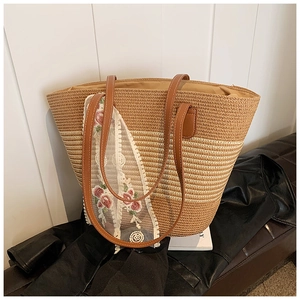 Detailed close-up of straw tote bag with floral embroidery lace and gradient brown finish