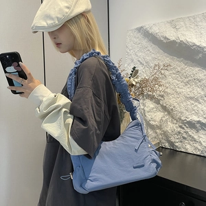 Detail of blue nylon pleated shoulder bag with drawstring design and soft textured fabric