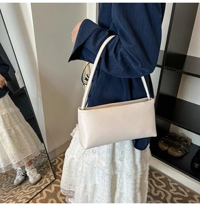 Minimalist beige baguette shoulder bag worn by model with casual stylish outfit