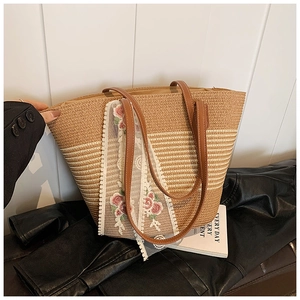 Close-up of woven straw tote bag featuring delicate floral embroidery and leather handles