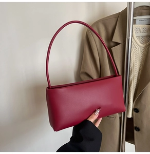 Detail of dark red matte leather baguette bag paired with a beige office suit