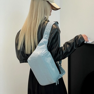 Gros plan du sac bandoulière en nylon bleu clair avec fini satiné et double fermeture