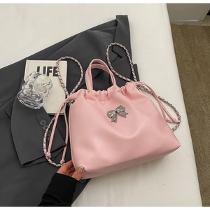Detailed view of pink ruched bag featuring silver metal bow and leather chain strap
