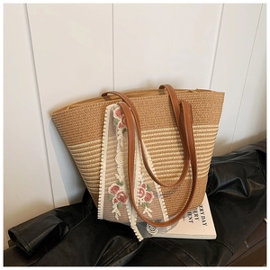 Close-up of woven straw tote bag featuring brown leather handles and white lace floral scarf