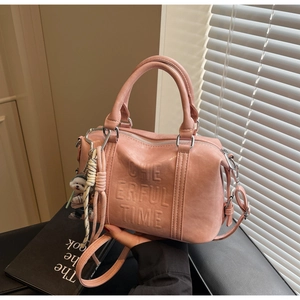 Detail view of pink PU leather boston bag with embossed text and plush puppy charm