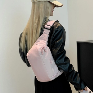 Détail du sac bandoulière en nylon rose clair avec sangle réglable et fermetures éclair
