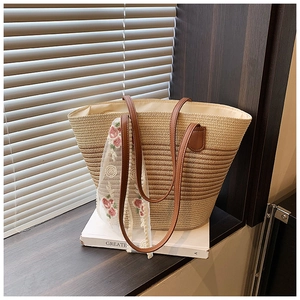 Detail of striped straw tote bag with brown leather handles and flower lace scarf
