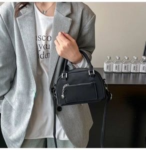 Dettaglio della borsa a tracolla nera con hardware argento e ciondolo a forma di cuore