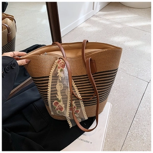 Detail of straw tote bag with black stripes, leather straps and lace floral ribbon