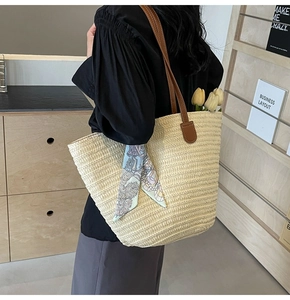 Detailed texture of large straw tote bag with brown leather straps and blue silk scarf decor